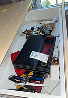 Drawer view with wristwatches, wallets, coin purse, sunglasses, coins