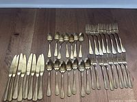 All 30 gold-tone flatware pieces laid out: knives, forks, tablespoons, teaspoons