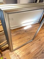 Front view of rectangular mirror leaning against wall showing full frame and glass