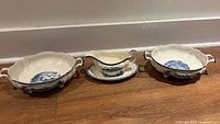 Three serving pieces: two handled bowls, gravy boat on saucer