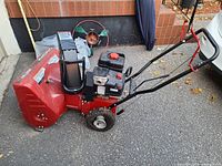 Side view of red Canadiana 800/24 snowblower showing engine, chute and handlebars
