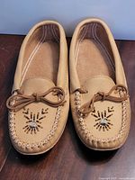 Top view of both moccasin slippers showing beadwork and lace bow
