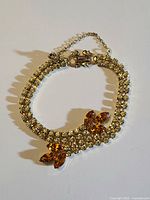 Front view showing rhinestone rows, leaf motifs, clasp and chain