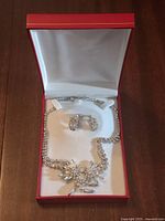 Necklace and earrings set displayed inside red box, clasp visible