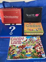 All five board games laid out: Adverteasing, Read My Lips, Cranium Cadoo, Candy Land and blue question-mark box