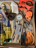 Overview of box showing variety of tools including stapler, gauge, scissors, screwdrivers