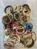Top view of container filled with assorted bracelets showing variety of styles and materials