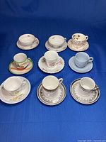 All nine cup and saucer sets displayed on blue backdrop