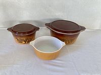Three Pyrex Old Orchard casseroles and two lids
