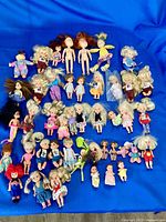 Group shot of entire lot of 43 dolls on blue background