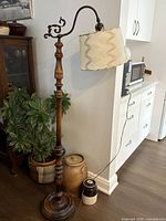 Full view of floor lamp showing wood base, column, metal arm, shade