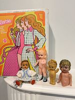 Front view of Barbie trunk case with four small dolls posed in front