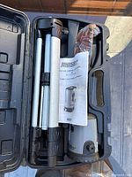 Kit contents inside case: folded tripod, manual, safety glasses, laser level base visible