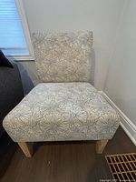 Front view of floral print armless chair showing upholstery and legs