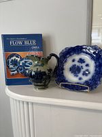 Book, pitcher and plate on shelf