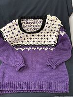 Full view of sweater laid flat showing body, sleeves, fair-isle yoke, and ribbing