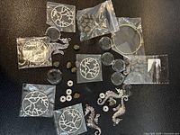 Overview of metal pendant blanks, charms, beads and cabochons on black surface