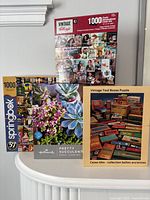 Front view of all four puzzle boxes standing to show titles, piece counts and imagery