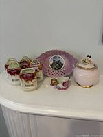 Group shot showing spice canisters with lids, miniature creamer, sugar bowl and souvenir plate