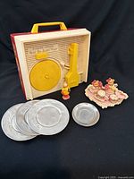 Overview showing Fisher-Price record player, stack of aluminum plates, teddy bear figurines