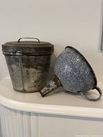 Lidded pudding pan and graniteware funnel side by side