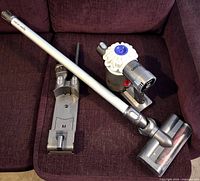 All components arranged on sofa: motor unit, wand, floor head, dock, crevice tool