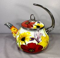 Front left view of floral enamel tea kettle showing body, lid, spout and handle