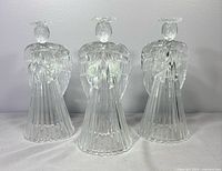 Front view of three glass angel candle holders