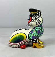 Left side view of multicolour cat figurine with hat, rainbow flank and gold boots
