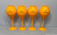 Front view of four orange Veuve Clicquot plastic goblets