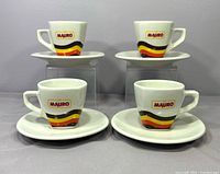 Front view of four cups on saucers showing logos