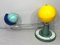 Full view of orrery showing Sun, Earth globe in blue hood, arm and base