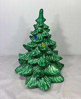 Front view of green ceramic Christmas tree with few colored bulbs