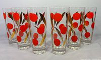 Front view of seven matching highball glasses showing red polka dots and gold leaf design