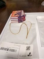 Sealed ornament pouch showing book stack ornament and gold cord