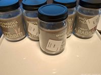 Five glass jar candles with grey lavender wax and black lids placed on tray