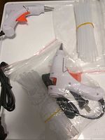 Two mini glue guns with cords, glue sticks bundled