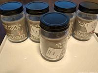 Five lavender scented jar candles with rabbit labels and black lids displayed on tray