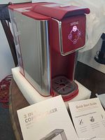 Coffee maker with drip tray and manuals visible