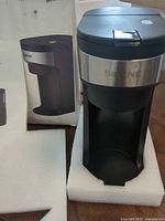 Coffee maker standing in foam insert beside box