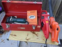Open Sears Craftsman toolbox with Walter grinder, discs, red hedge trimmer, orange Black & Decker leaf blower