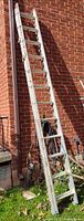 Full view of the aluminum ladder leaning against a brick wall