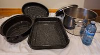 Group view: oval roasting pan with lid, rectangular roasting pan, stainless stockpot with lid