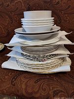 Stack of mixed plates and bowls separated by paper towels