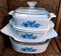 Stacked view showing two square dishes and one oblong dish with blue floral pattern and glass lid