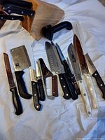 Group view of assorted knives, cleaver, slicers, two white-handled knives