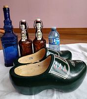 All items: blue bottle, two brown swing-top bottles, green wooden clogs