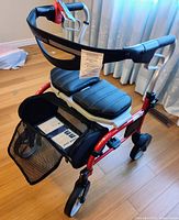 Front angled view of red Evolution rollator with black seat and mesh bag