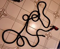 Coiled black expandable garden hose on tile floor