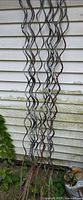 Full length view of grouped wavy metal stakes leaning against siding